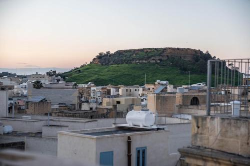 a view of a city with a hill in the background at Bell & Beam - A Timeless Gozitan Stay in Victoria in Victoria