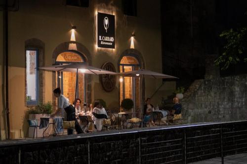 a group of people sitting at a restaurant with umbrellas at Morelliana4Rooms in Scansano