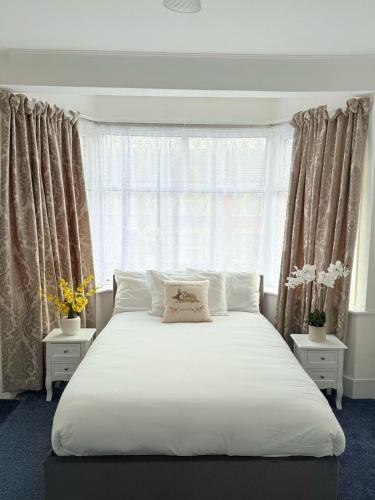 a bedroom with a large white bed and a window at Luxury House in Ilford 21 minute Train journey from Central London in Ilford