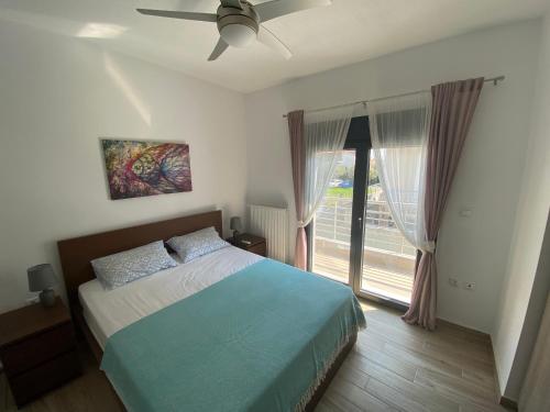 ネア・カリクラティアにあるSanta Marina Beach Houseのベッドルーム1室(天井ファン、窓付)