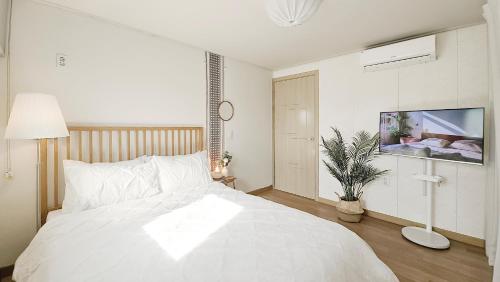 a bedroom with a white bed and a tv at Lucky Vicky House in Seoul