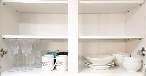 a white cabinet filled with bowls and other kitchen utensils at Lucky Vicky House in Seoul
