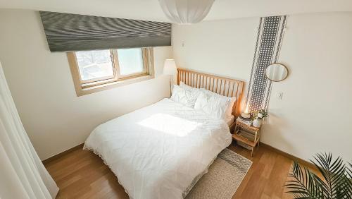 a white bed in a bedroom with a window at Lucky Vicky House in Seoul