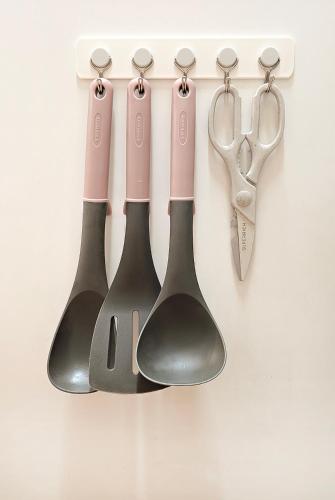 four measuring spoons and a pair of scissors hanging on a wall at Lucky Vicky House in Seoul