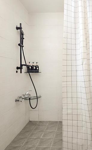 a shower with a hose in a white tiled bathroom at Lucky Vicky House in Seoul