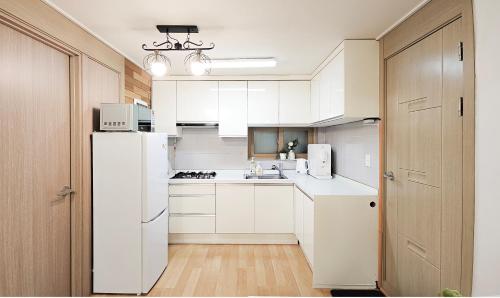 a kitchen with white cabinets and a white refrigerator at Lucky Vicky House in Seoul