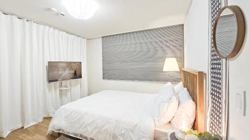 a white bedroom with a bed and a television at Lucky Vicky House in Seoul