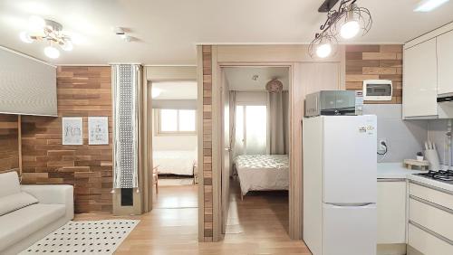 a kitchen with a refrigerator and a room with a bed at Lucky Vicky House in Seoul