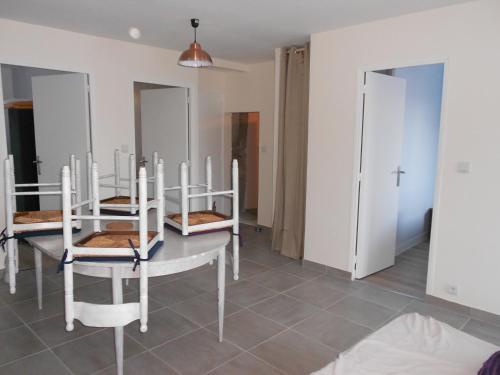une salle à manger avec des chaises blanches et une table dans l'établissement Location à la campagne, à Lestomble