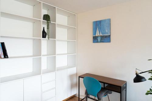 Cette chambre comprend un bureau et une chaise bleue. dans l'établissement Appartement 1 chambre, terrasse, proche Tram, à Bordeaux