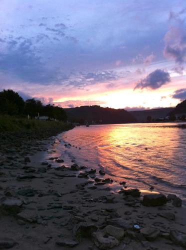 a sunset on the shore of a body of water at Rheinhotel St. Goar in Sankt Goar