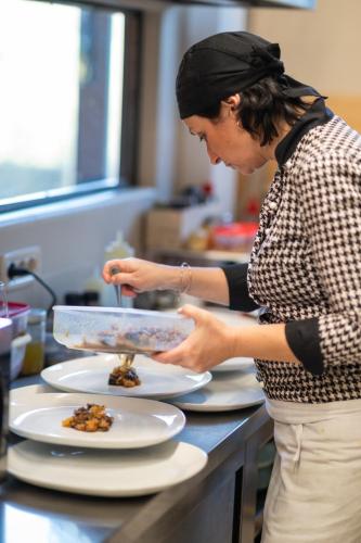 a woman standing in a kitchen preparing food on plates at Morelliana4Rooms in Scansano