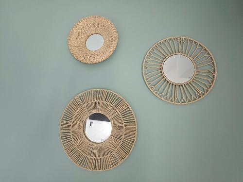 three mirrors on a white wall with a rattan mirror at Casa Galilea חופשה גלילית עם בריכה פרטית וג'קוזי in Parod