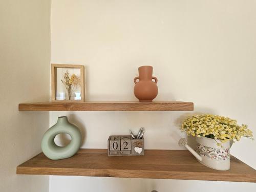 a shelf with vases and a clock and flowers at Casa Galilea חופשה גלילית עם בריכה פרטית וג'קוזי in Parod