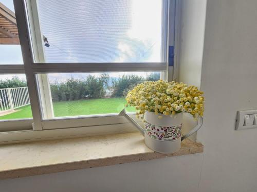 a vase with yellow flowers sitting on a window sill at Casa Galilea חופשה גלילית עם בריכה פרטית וג'קוזי in Parod