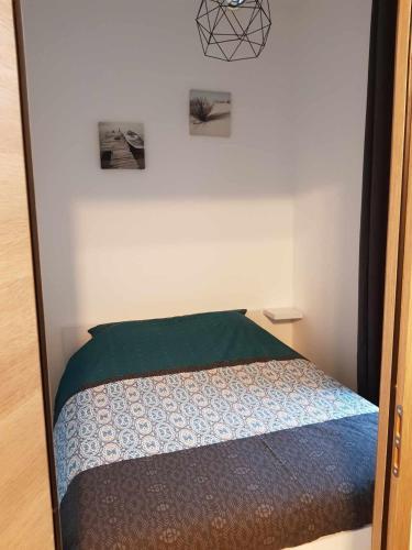- une petite chambre avec un lit et une couverture verte dans l'établissement Basilique V, à Douvres-la-Délivrande