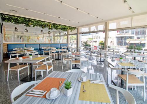 a restaurant with tables and chairs and windows at Hotel Velvet Plaza in Guadalajara