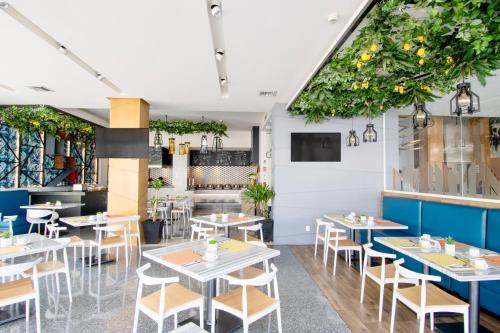 a restaurant with tables and chairs and plants at Hotel Velvet Plaza in Guadalajara