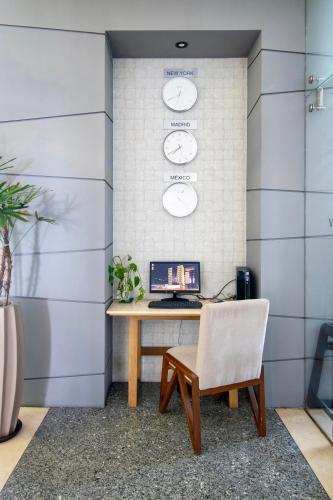 an office with a desk and a chair and clocks at Hotel Velvet Plaza in Guadalajara