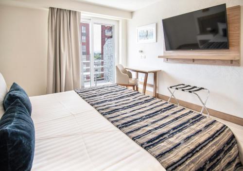 a bedroom with a bed with a television on the wall at Hotel Velvet Plaza in Guadalajara