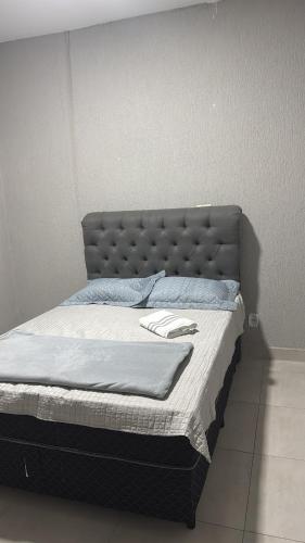 a bed with a gray headboard in a room at Casa temporada 2 in Trindade