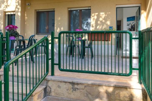 a green fence in front of a building with tables and chairs at Appartamenti DueC in Trapani