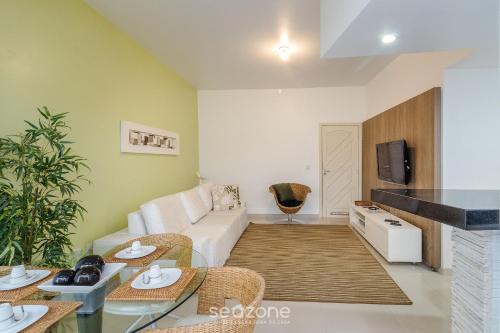a living room with a white couch and a tv at Apto térreo a 5min da Praia do Forte EMA101 in Škorak