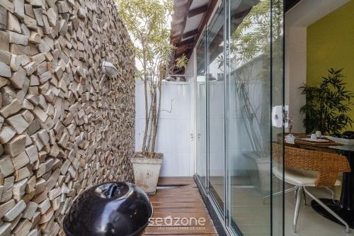 a room with a glass door and a stone wall at Apto térreo a 5min da Praia do Forte EMA101 in Škorak