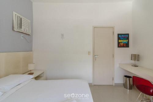 a white room with a bed and a red chair at Apto térreo a 5min da Praia do Forte EMA101 in Škorak