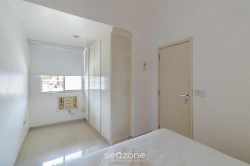 a white room with a bed and a door at Apto térreo a 5min da Praia do Forte EMA101 in Škorak