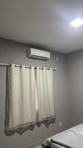 a room with a bed and a window with a curtain at Casa temporada 2 in Trindade