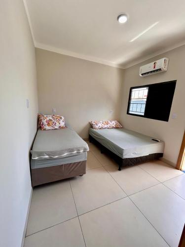 a room with two beds and a flat screen tv at Cantinho Guimarães in Olímpia