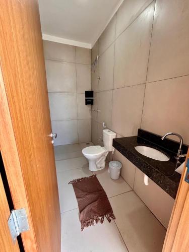 a bathroom with a toilet and a sink at Cantinho Guimarães in Olímpia