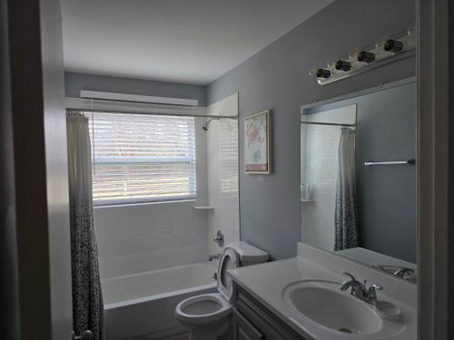 a bathroom with a sink and a toilet and a window at Cozy Haven in Hampton Roads Near Beaches, Military Bases & Historic Sites in Hampton