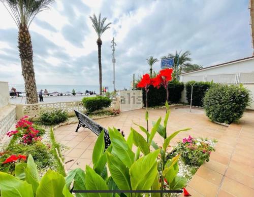 a park with flowers and a bench near the beach at Blue house 1ª linea playa in Torrevieja