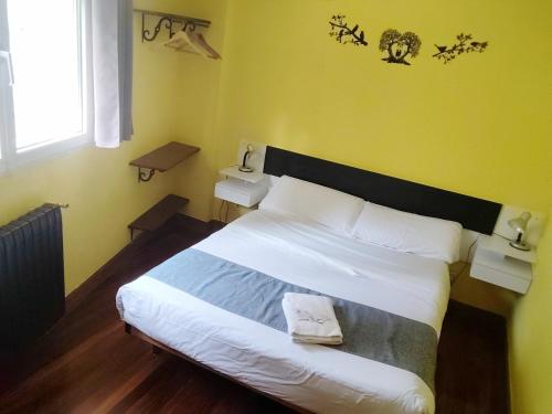 a bedroom with a large white bed with yellow walls at Txoko Maitea Pentsioa in Urnieta