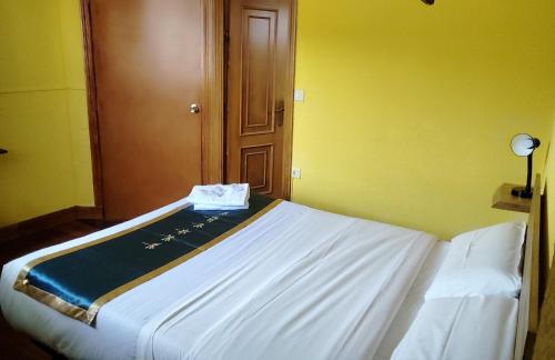 a white bed in a room with a yellow wall at Txoko Maitea Pentsioa in Urnieta