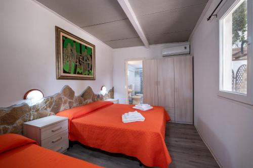 Un dormitorio con dos camas con sábanas naranjas. en Appartamento Depandance 2 Villa Ada Punta Prosciutto, en Punta Prosciutto