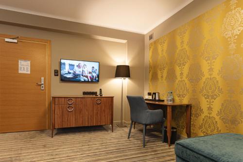 a hotel room with a bed and a desk and a television at Hotel Cristal Białystok in Białystok