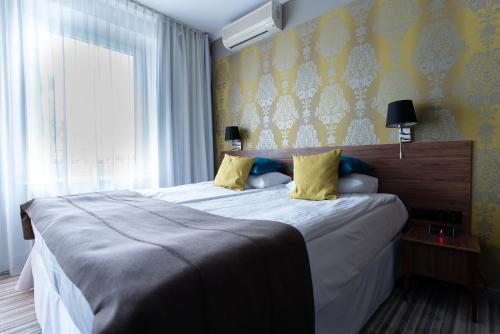 a bedroom with a large bed with yellow wallpaper at Hotel Cristal Białystok in Białystok