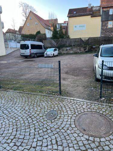 two cars parked in a parking lot next to a fence at CozyHome Hauptmarkt Apartments in Gotha