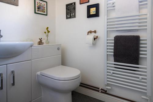 a white bathroom with a toilet and a sink at Vibrant 2 Bed, 2 Bath Home, Just Minutes to Town! in Ross on Wye