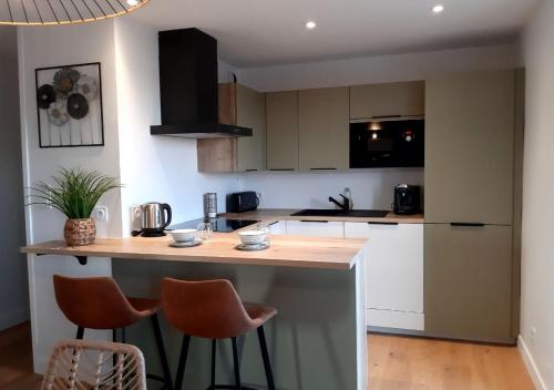 une cuisine avec un îlot et deux tabourets de bar dans l'établissement VUE MER panoramique sur la baie de St-Cast-le-Guildo, à Saint-Cast-le-Guildo