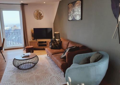 un salon avec un canapé et une télévision dans l'établissement VUE MER panoramique sur la baie de St-Cast-le-Guildo, à Saint-Cast-le-Guildo