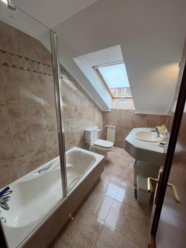 a bathroom with a tub and a sink and a toilet at Gestiona2R- Casa grande para 12 en Llanes 6 dormitorios Jardín y espacio exterior in Llanes