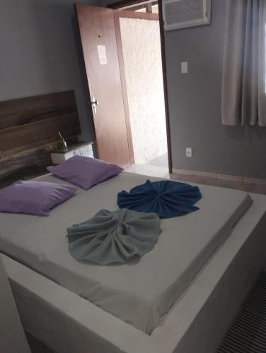a bed with two blue pillows on top of it at Pousada Rout Bikers Penedo in Penedo