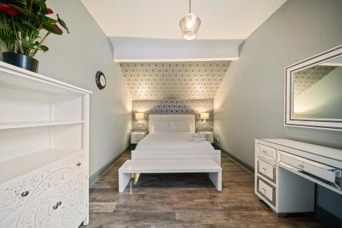 a white bedroom with a bed and a mirror at Spacious, Central Townhouse with Hot Tub & Free Parking in Lytham St Annes