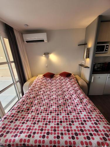 Ce lit se trouve dans un dortoir doté d'un couvre-lit rouge et blanc. dans l'établissement La Mer, à Saint-Raphaël