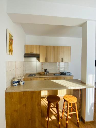 a kitchen with a wooden island with two stools at Apartamenty Gawędówka in Krościenko
