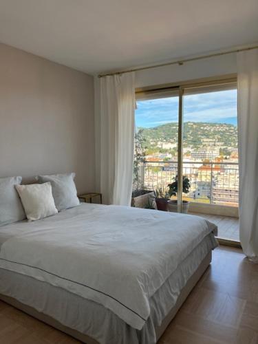 une chambre avec un grand lit et une grande fenêtre dans l'établissement Celeste Cannes Centre 700m du Palais des Festivals, à Cannes